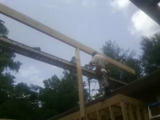 Carpenter setting a ridge beam over a new addition frame — Ice Dam Removal by Roofing Brothers in Pearland