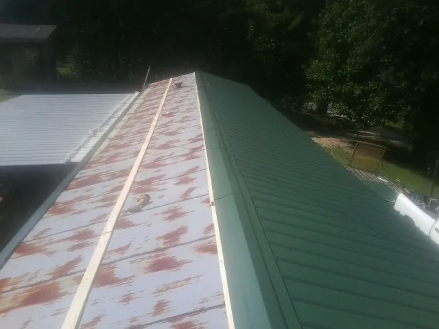 Old rusted panels beside newly installed green metal roofing — Wind Damage Roof Repair by Roofing Brothers in Pearland