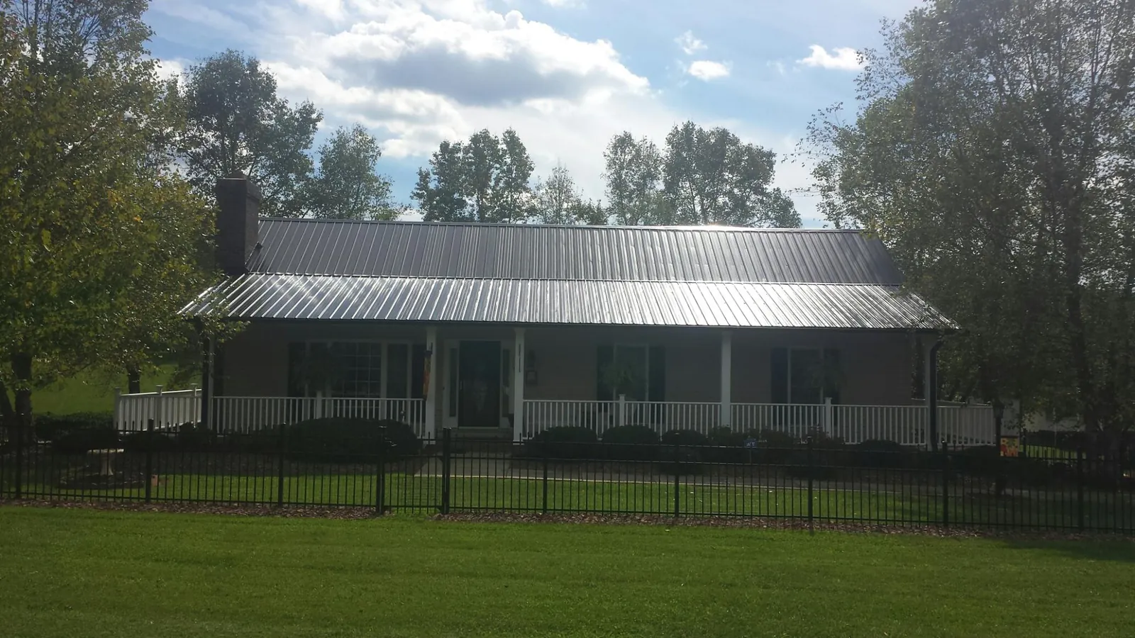Gray metal roof on a brick ranch with a full width front porch — Gutter Guard Installation work by our crew in Pearland